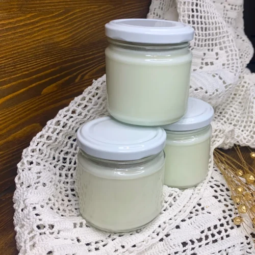 Zestaw 3 naturalnych jogurtów kozich 160 ml w szklanych słoiczkach, na rustykalnym tle. Produkty z mleka koziego z Gospodarstwa Yagi.