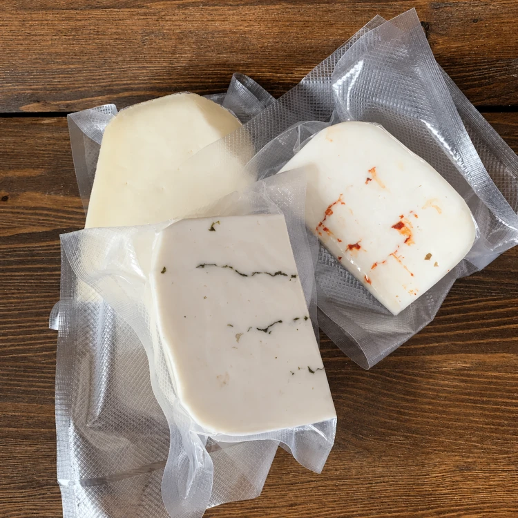Trzy sery kozie Hela na drewnianym tle – naturalny, z chili i z czosnkiem niedźwiedzim, zestaw 3 × 150 g